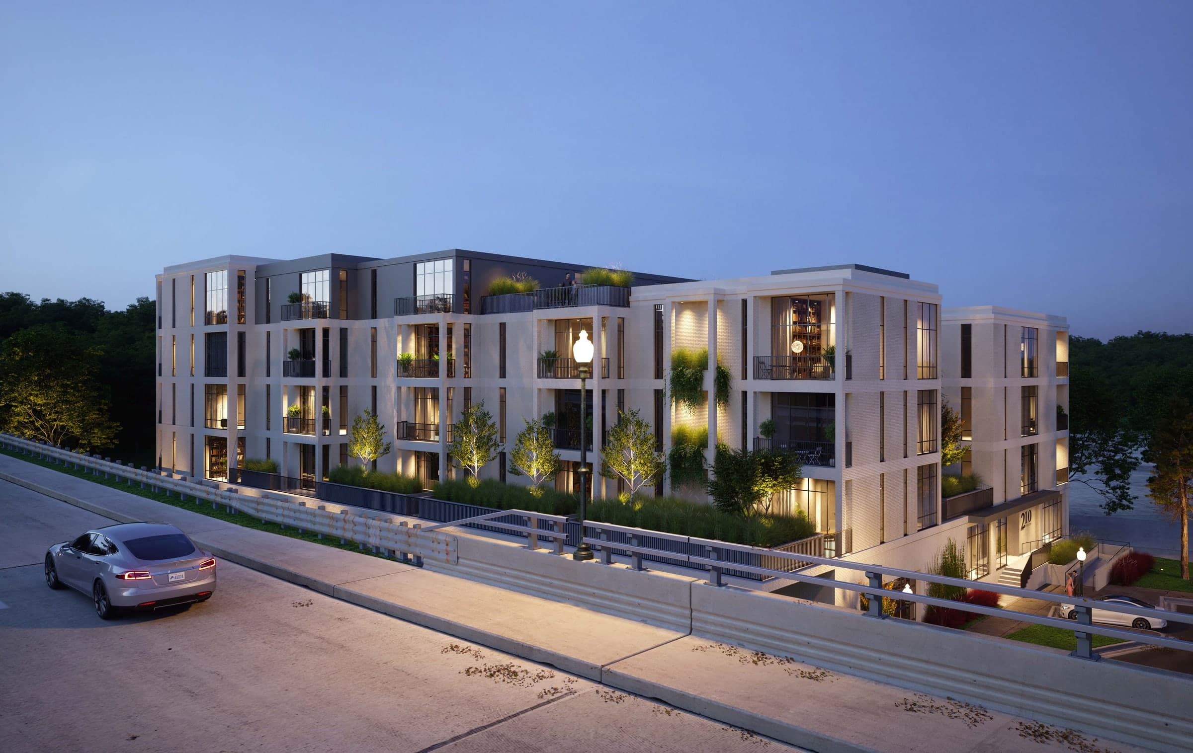 210 Diversion multi-family residence at dusk, white brick elevation with recessed planted balconies and warm lit interiors
