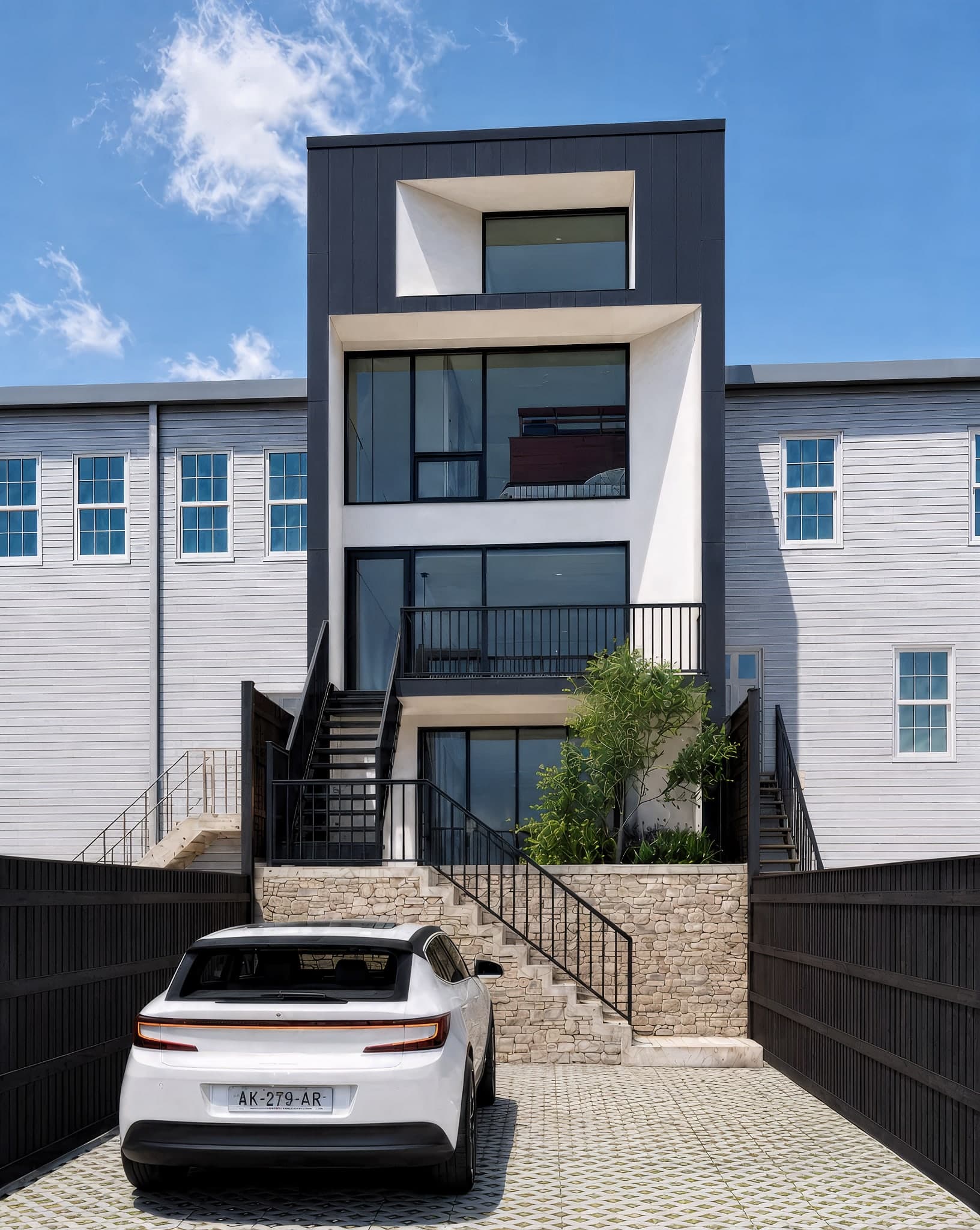 Daytime rear elevation of the Washington DC row house addition with dark cladding, floor-to-ceiling glass, and stone landscape steps