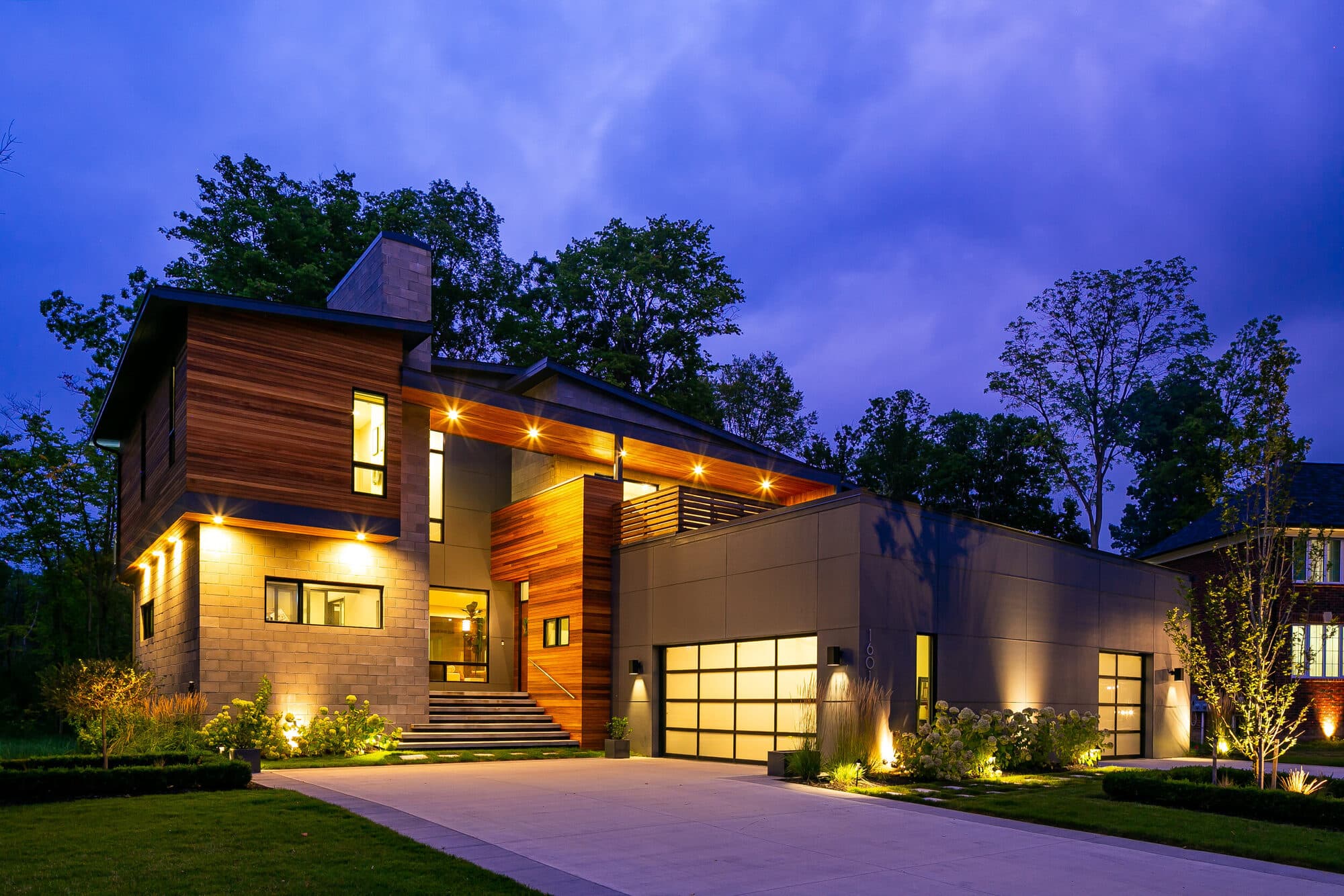 Modern custom residence in Rochester Michigan at twilight with stone, wood, and glass facade